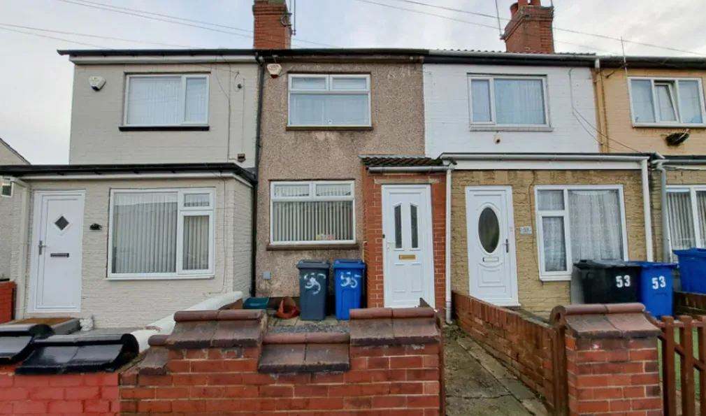 The front of 55 Hunt Lane: a mid terrace house with a pebbledash front, white uPVC door and windows, two wheelie bins in the yard and a low red brick garden wall.