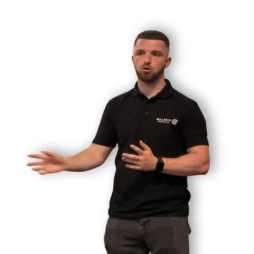 Connor Blades in a black Bullseye Properties polo shirt, mid sentence with both hands raised as he explains something.
