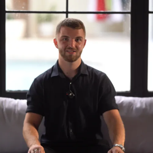Connor Blades, founder of Bullseye Properties, sitting in front of a window in a dark polo shirt.
