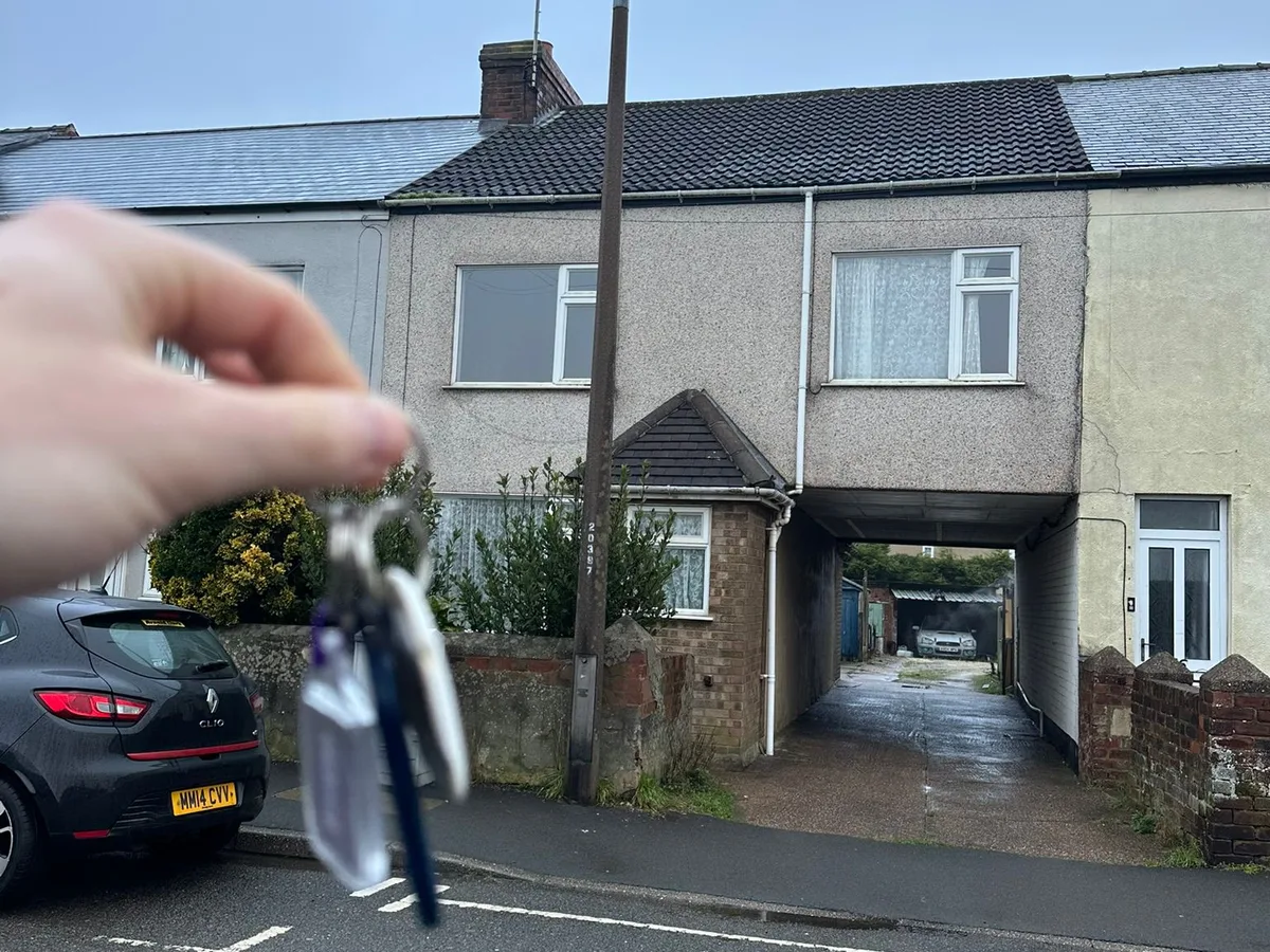 Keys held up in front of a house on Boughton Lane.